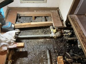 劣化した床下の鉄管を切断して配管更新する作業中
